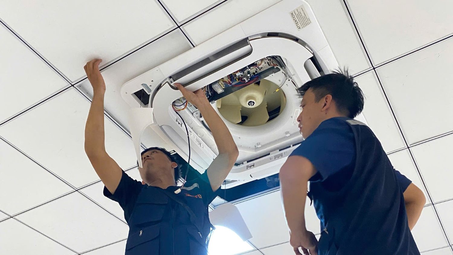 Hai kỹ thuật viên TFIX bảo trì máy lạnh âm trần tại văn phòng